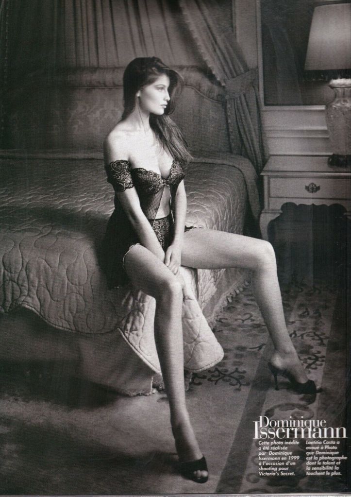 Modèle posant sur un lit en lingerie noire, illustrant une atmosphère sensuelle et élégante. Il s'agit d'une photo de Laetitia Casta, prise lors d'un shooting pour Victoria's Secret en 1999.