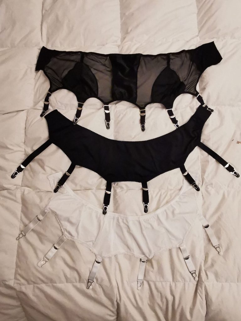 Deux porte-jarretelles et un serre-taille posés les uns au dessus des autres : un Rétro Swing de la Dame de France, un Liz de What Katie Did et un Simplon de En Voile.