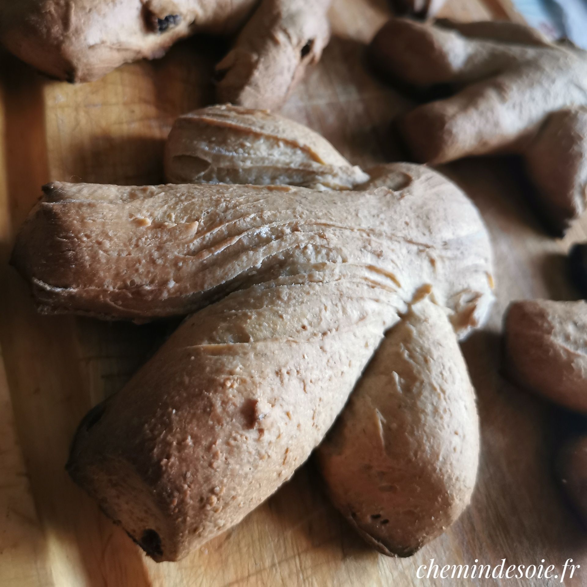 Image en gros plan de brioches en forme de bonhomme, posées sur une planche. Version non retouchée.