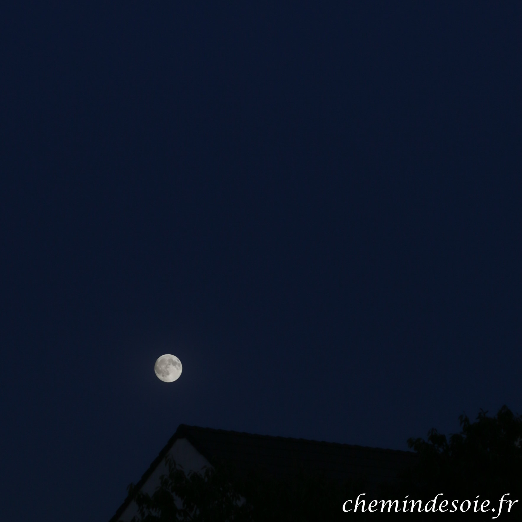 Vue de la Lune montante, au dessus d'une maison.